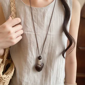 Vintage leather cord necklace with a heart-shaped resin pendant worn on a linen dress.