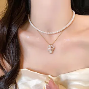 Primo piano di collana di perle stile francese con pendente a cesto di fiori.