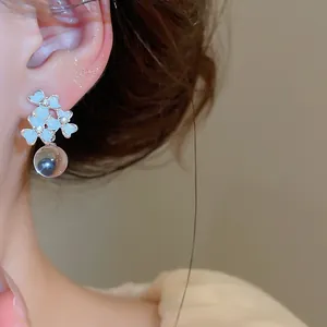 Close-up of French resin flower earrings with sparkling rhinestones and drop bead.
