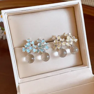 Detailed close-up of French-style resin flower earrings with sparkling rhinestones in a box