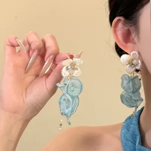 Detailed view of elegant light blue chiffon flower tassel earrings on a model (81 chars)