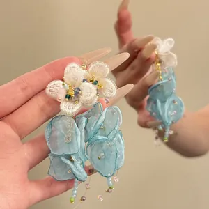 Detail view of light blue chiffon flower earrings with delicate bead tassels