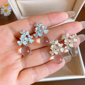 Close-up of French style resin flower earrings with rhinestones and bead drops.