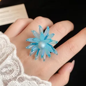 Elegante orecchino a fiore in vetro blu stile francese con perla mostrato sulla mano