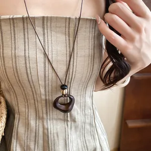 Close-up detail of retro resin heart pendant and wood beads on a brown leather cord necklace