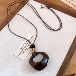Macro view of a retro resin ring pendant necklace with wood beads and brown wax cord.