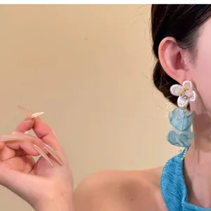 Close-up view of a model wearing blue chiffon flower tassel earrings in dopamine style