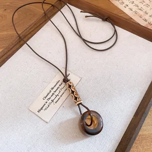 Detailed view of vintage resin ring pendant on a brown leather cord sweater necklace.