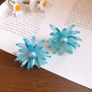 Dettaglio macro ravvicinato di orecchini a fiore in vetro blu con perla centrale