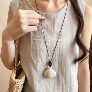 Close-up of a vintage resin pendant necklace with wood beads worn by a model in soft light