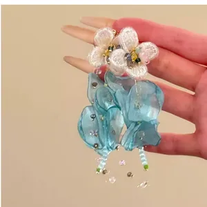 Close-up view of elegant blue and white chiffon flower tassel earrings with pearl beads
