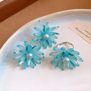 Dettaglio ravvicinato del set di gioielli a fiore blu con petali di vetro e perla centrale.