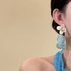 Detailed view of elegant chiffon flower tassel earrings worn by a model in blue dress