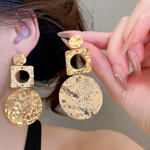 Detail view of 18k gold plated earrings with hammered texture and geometric shapes