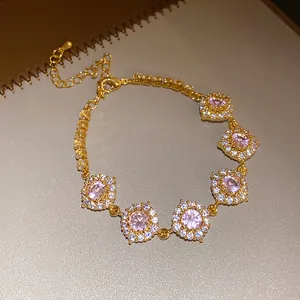 Gros plan d'un bracelet doré avec des fleurs en zircon rose et des cristaux brillants
