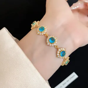 Détail rapproché d'un bracelet en or de luxe avec des fleurs en zircon bleu au poignet