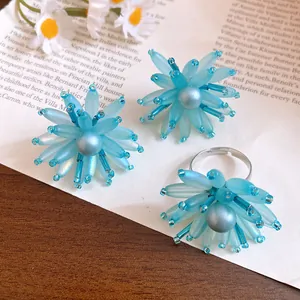 Dettaglio degli orecchini e dell'anello con petali in vetro blu e una perla centrale