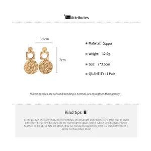 Detailed macro view of gold textured geometric round drop earrings with size measurements