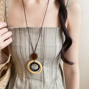 Close-up view of a vintage resin pendant necklace with leather cord worn by a model