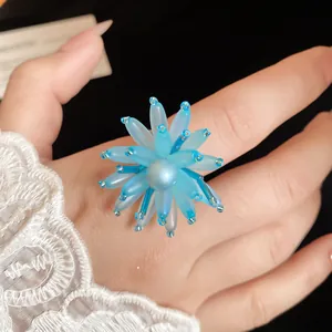 Vista dettagliata di un gioiello a fiore in vetro blu con centro di perla su mano con pizzo