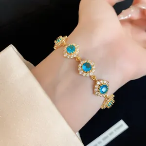 Gros plan d'un bracelet fleur en or avec pierres de zircon bleu au poignet
