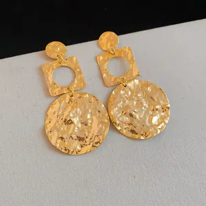 Close-up of gold-plated geometric earrings with a hammered wrinkled texture finish
