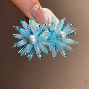 Dettaglio squisito di orecchini a petali in vetro blu con un accento di perla centrale.
