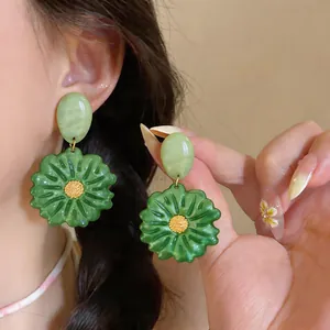 Primo piano dettagliato di orecchini a fiore in resina verde indossati all'orecchio