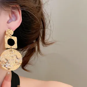 Close-up detail of 18k gold-plated hammered geometric round earrings on a model