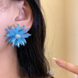 Vista macro dettagliata di un orecchino a fiore in vetro azzurro con una perla