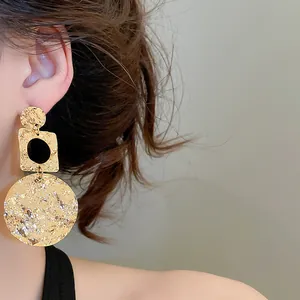 Detail shot of 18k gold plated geometric drop earrings featuring a unique crinkled texture