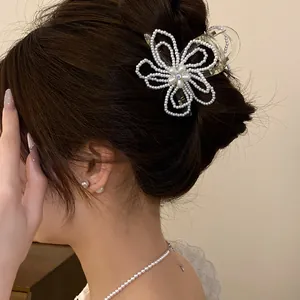 Close-up of an elegant pearl flower hair claw clip worn in a stylish bun hairstyle