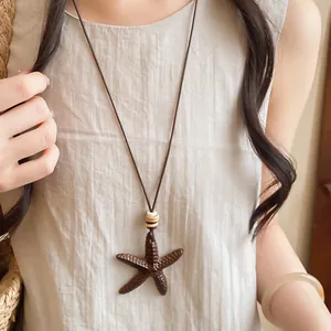 Detailed view of a vintage brown starfish pendant necklace on a long leather cord.