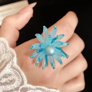 Dettaglio di un anello a fiore di perline blu con centro di perle sulla mano di una modella.