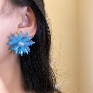 Vista dettagliata dell'orecchino a fiore in vetro blu con perla sulla modella