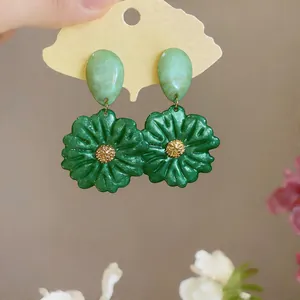 Dettaglio ravvicinato di orecchini a fiore in resina verde con centro dorato e ago