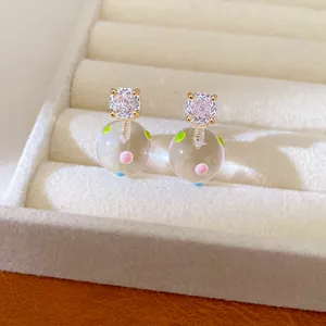 Macro view of dainty 18k gold-plated stud earrings with colorful dotted glass balls