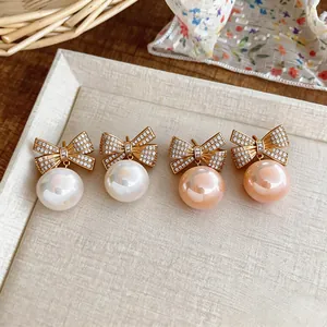 Makroansicht von eleganten Vintage Zirkon Schleifen Perlenohrringen in Weiß und Rosa.