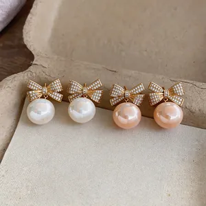 Detailansicht eleganter Zirkon-Schleifen-Ohrringe mit Perlen in Weiß und Rosa in Vintage-Optik.