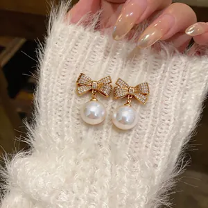 Detailaufnahme von Vintage-Schleifenohrringen mit Zirkonia und weißen Perlen