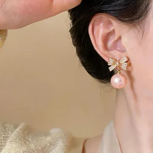 Makroansicht eleganter goldener Schleifenohrringe mit Zirkonia und rosa Perlen