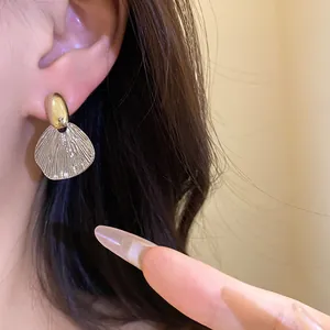 Gros plan détaillé montrant la boucle d'oreille pendante vintage en feuille dorée