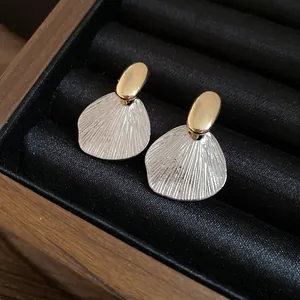 Gros plan détaillé montrant la texture métallique des boucles d'oreilles feuilles bicolores