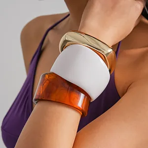Close-up of vintage chunky resin and gold metal bangles worn on a model's arm.