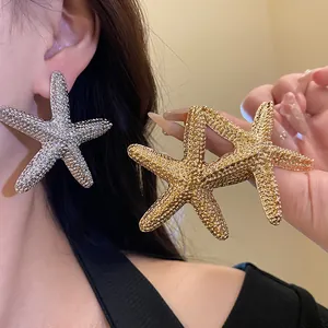 Detail of large textured starfish stud earrings shown worn and held in gold and silver