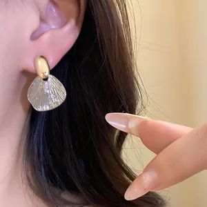 Gros plan détaillé de boucles d'oreilles pendantes dorées avec texture de feuille