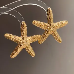 Close-up of golden starfish stud earrings with intricate textured surface details