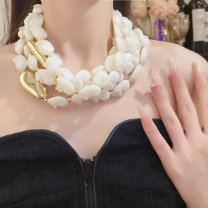 Close-up of vintage multi-layer white acrylic bead necklace with gold accents on model