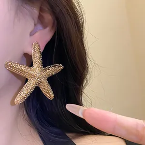 Close-up of a textured gold starfish earring worn by a model in an elegant vintage style