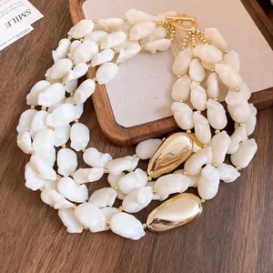 Detail view of multi-layer retro necklace with cream acrylic beads and golden pendants.